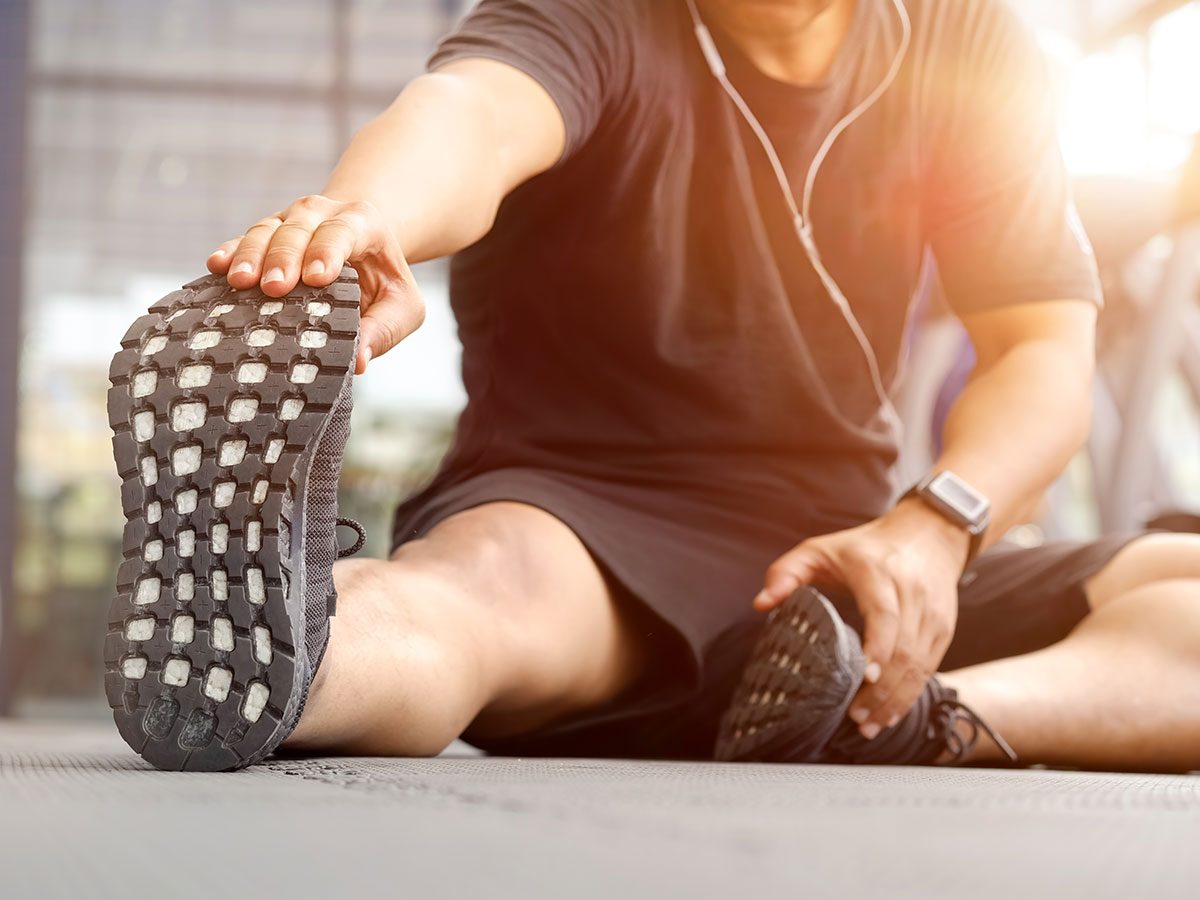 Walking 10,000 steps a day improves flexibility - man stretching at gym