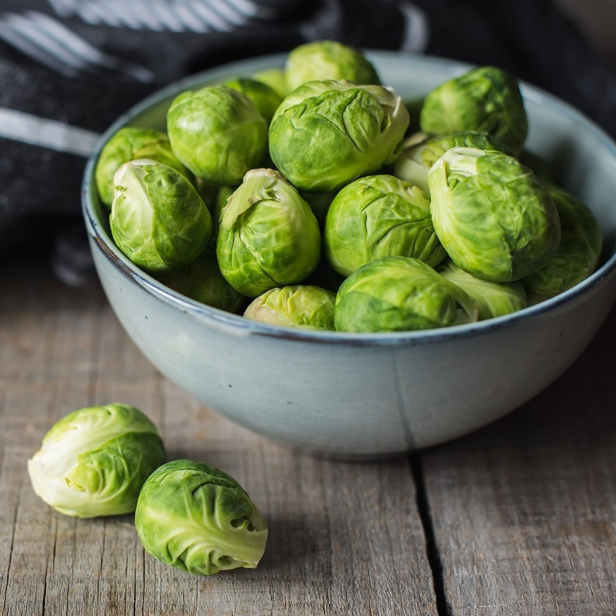 Bowl of Brussels sprouts and napkin on a rustic wooden table.